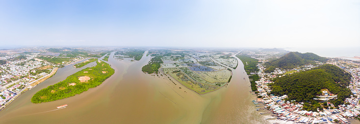 Aerial view Ha Tien city skyline from above, Mekong river delta, South Vietnam. Scenic river water canals flooding on the rice fields. Clear blue sky.