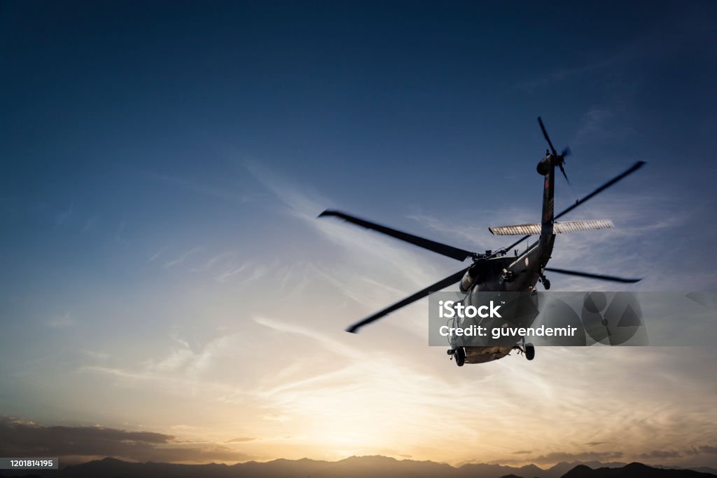Photos Military Helicopter flying against sunset Helicopter Stock Photo