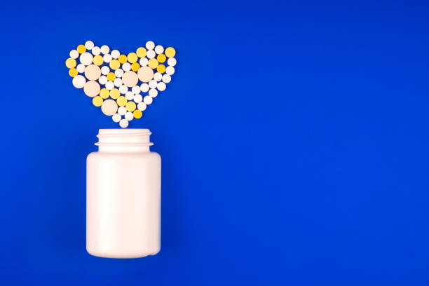 青い背景に心臓の形で医療多色の丸薬の山でパック - perscription capsule frame pill ストックフォトと画像