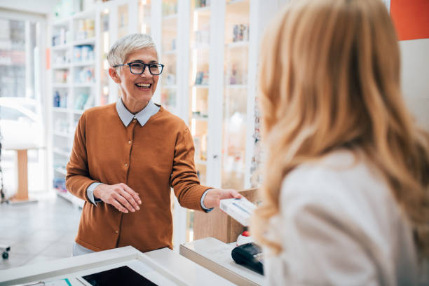 reife frau kauft ein medikament in der apotheke - apothekerin stock-fotos und bilder