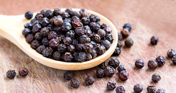 istock Black peppercorn in wooden spoon on old wood table. 1201820081