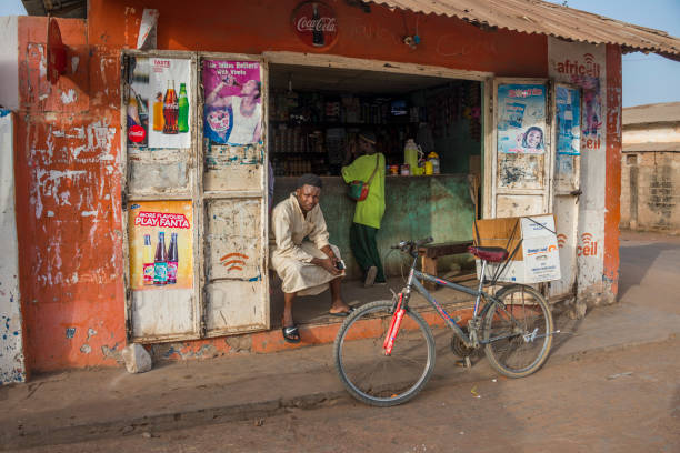 Banjul, Gambia - may 09, 2017: Scene with bicycle and people in a grocery store in a populous city neighborhood at sunset