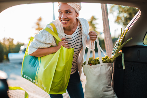 Young smiling girl taking groceries out of reusable shopping bags