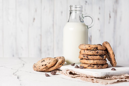 Tasty chocolate chip cookies with milk on white rustic background