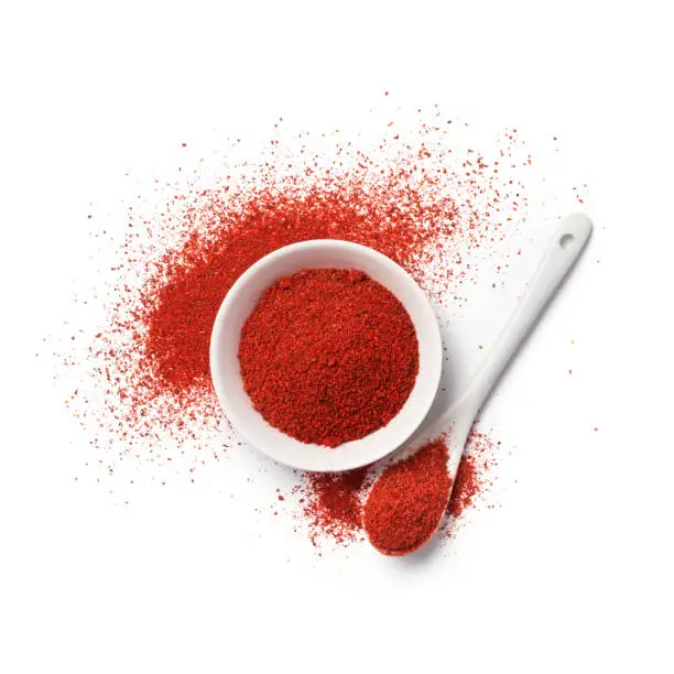 Top view of red pepper powder in bowl for aromatic food isolated on white background