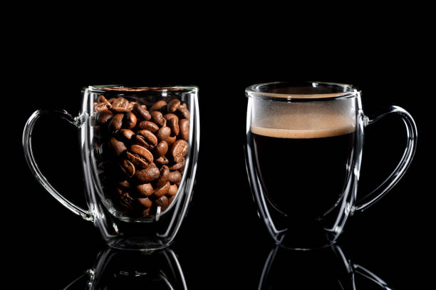 istock composition of two cups with coffee on a black background. left side cup with coffee bean side view, right side cup with finished coffee side view. Black background 1201828132