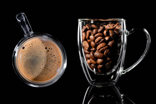 istock composition of two cups with coffee. on the left is a cup with finished coffee, top view, on the right is a cup with coffee grain side view. Black background 1201828316