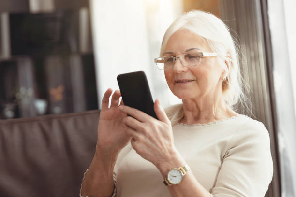 istock Beautiful senior woman texting at home 1201828555