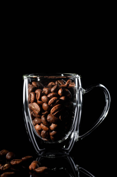 istock Coffee bean in a transparent cup, next to coffee beans. side view on black background 1201828746