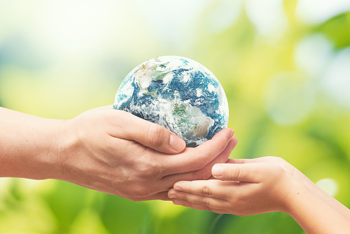 Man gives the Earth globe to the child. World environment day concept. Elements of this image furnished by NASA (https://www.nasa.gov/sites/default/files/styles/full_width_feature/public/thumbnails/image/westernhemisphere_geos_2019246_lrg.jpg)