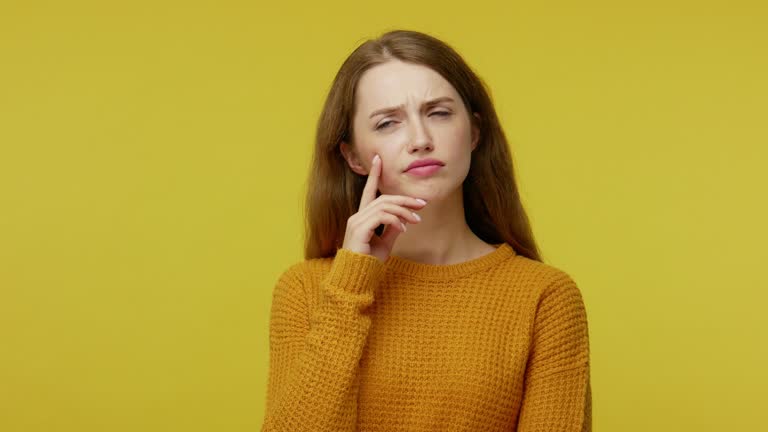 Let me think. Young pretty woman with brown hair in pullover standing minded and uncertain