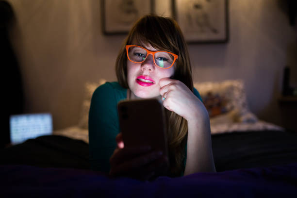 istock Cute girl with yellow phone looking at the screen 1201838606