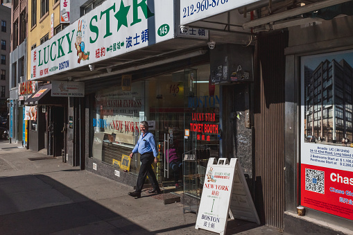 17 April 2019 - New York City, USA: Man walking out of a bus travel agency in Manhattan Chinatown
