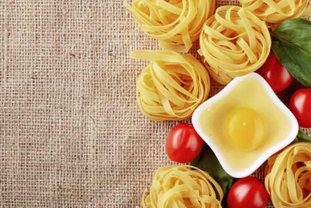 Raw egg noodles with tomato and basil. Top view, copy space.