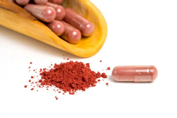 Red yeast rice or angkak or kojic rice powder and supplement capsule on white isolated background