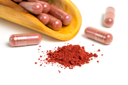 Red yeast rice or angkak or kojic rice powder and supplement capsule on white isolated background