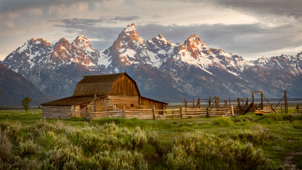 モールタン バーン サンライズ ウィズ ティトン 山脈 - western usa mountain peak landscape farm ストックフォトと��画像