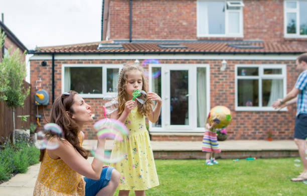 mother and daughter blowing bubbles - playing catch imagens e fotografias de stock
