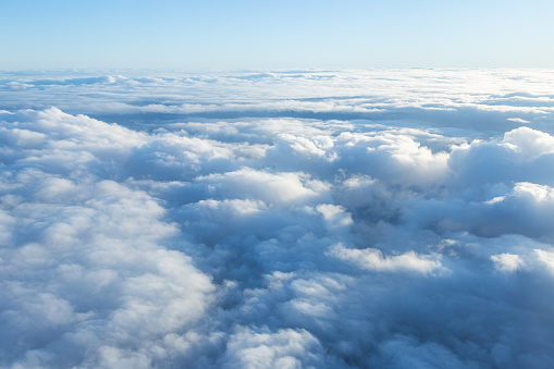 Fluffy clouds seen from above from the airplane window. 
Climatology and weather concept.