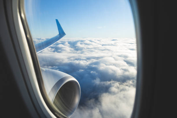 istock View from airplane window and the wing with sky over fluffy clouds. Flying and traveling concept background. 1201846682