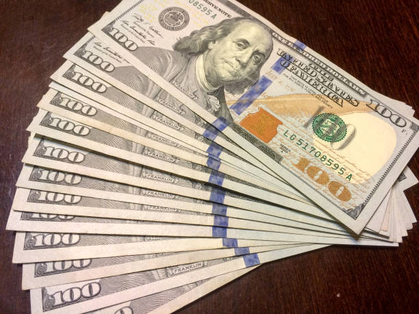 istock One hundred dollar bills fanned to the right on table 1201849991