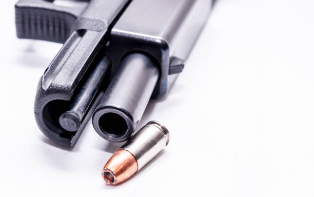 istock A black 9mm semi automatic with it's slide opened showing the barrel with a single 9mm hollow point bullet next to it 1201851693