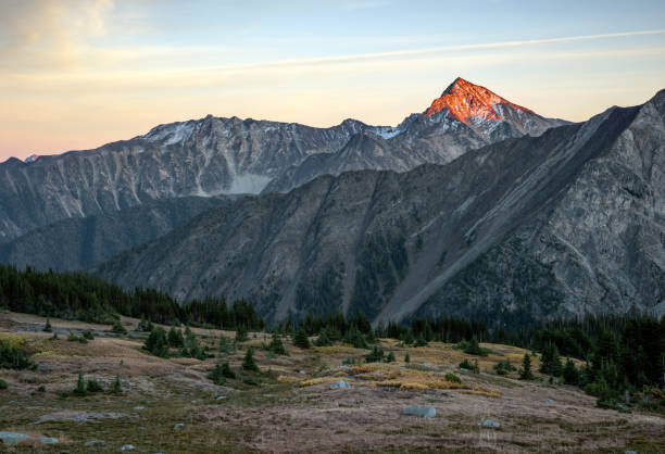 istock A single mountain peak illuminated by late afternoon sun with an alpine meadow in the foreground. 1201855963