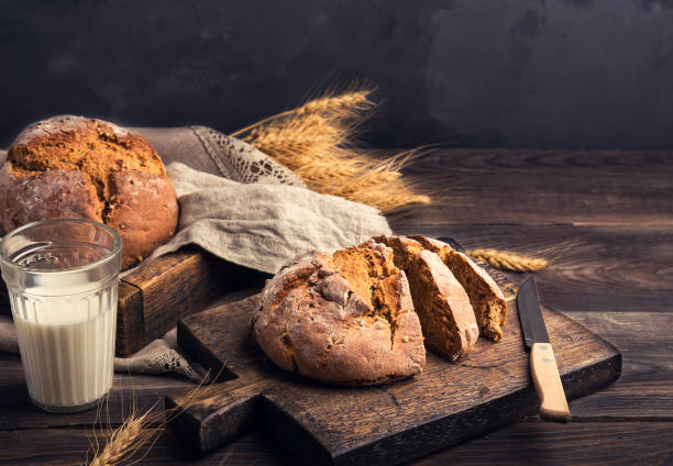 木製のまな板にコリアンダーの種を持つ自家製素朴なライ麦パン - milk bread ストックフォトと画像