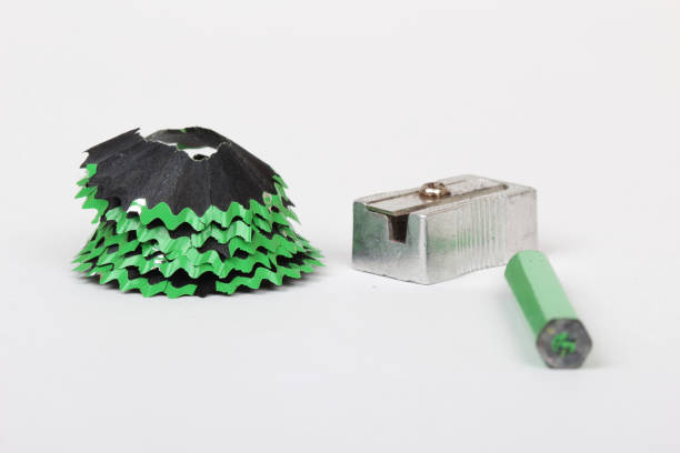 green pencil and shavings on white paper background