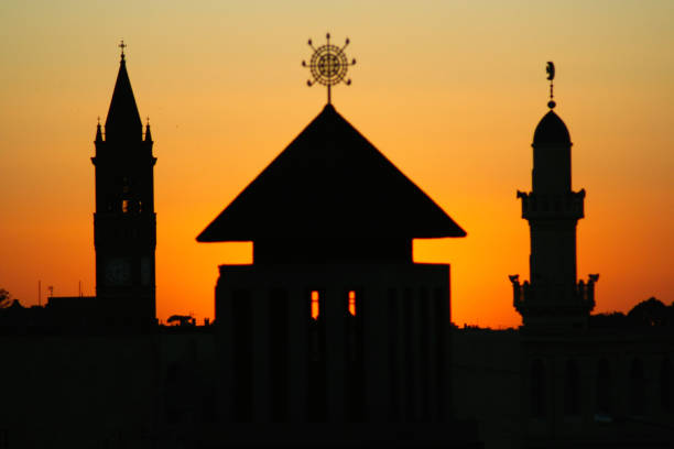 asmara skyline sunset, catedral ortodoxa enda mariam com, ao fundo, a torre do sino da igreja de nossa senhora do rosário e o minarete da grande mesquita kulafah al rashidan - our lady of africa - fotografias e filmes do acervo