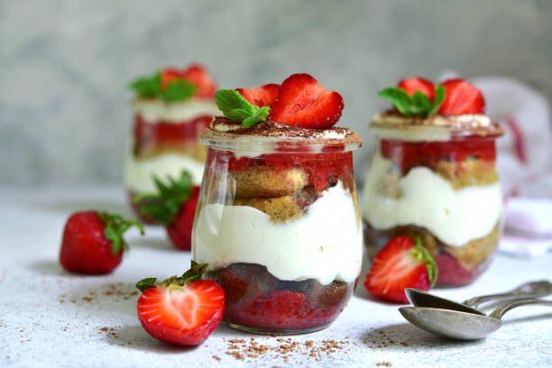 Summer tiramisu cake with fresh strawberry Summer tiramisu cake with fresh strawberry in a vintage jars on a light slate, stone or concrete background. trifle stock pictures, royalty-free photos & images