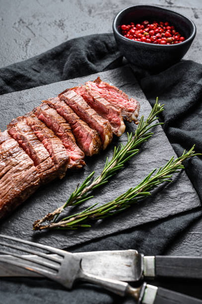 istock Roasted medium rare sliced flank beef steak. Black background. Top view 1201866674