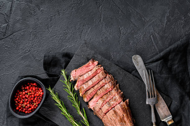 istock Sliced beef flank steak medium rare. Black background. Top view. Space for text 1201866881