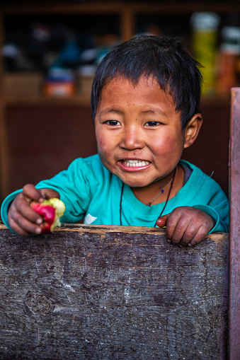Tibetan little boy sitting inside his father's shop, local village in Upper Mustang. Mustang region is the former Kingdom of Lo and now part of Nepal,  in the north-central part of that country, bordering the People's Republic of China on the Tibetan plateau between the Nepalese provinces of Dolpo and Manang.