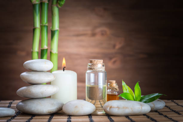 белый дзэн баланс камни, цветок орхидеи, бамбуковое растение и свеча на деревянном столе - spa treatment health spa zen like bamboo стоковые фото и изображения
