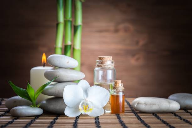 weiße zen gleichgewicht steinen, orchidee und bambus pflanzen auf dem holztisch - aromatherapie fotos stock-fotos und bilder