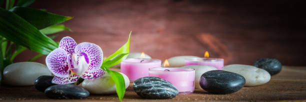 piedras de equilibrio zen blanco, una flor de orquídea, una planta de bambú y una vela sobre una mesa de madera - ayurveda massaging spa treatment massage oil fotografías e imágenes de stock