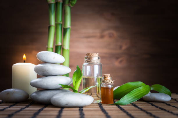 piedras de equilibrio zen blanco, una flor de orquídea, una planta de bambú y una vela sobre una mesa de madera - ayurveda massaging spa treatment massage oil fotografías e imágenes de stock