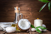 Spa still life with coconut, massage oil and candle on a wooden background