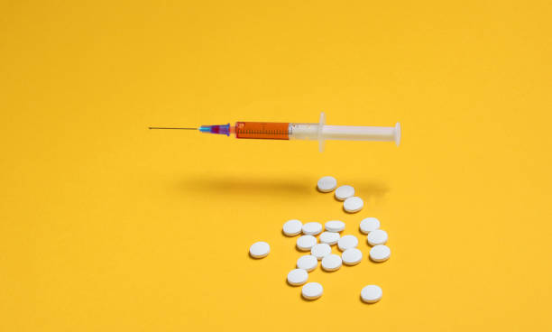 istock Medical minimalistic concept. Syringe, pills on yellow background. 1201872978