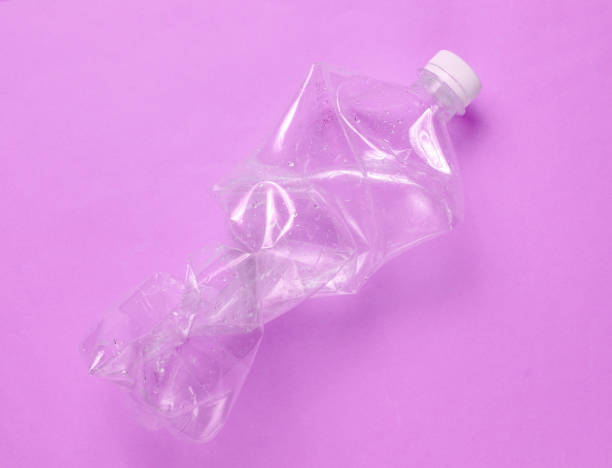 istock Minimalistic ecological concept. Crumpled plastic bottle on purple background. Environmental plastic pollution 1201873005