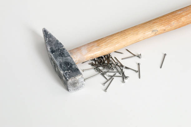 istock Silver shiny iron nails with hammer on white background. 1201875356