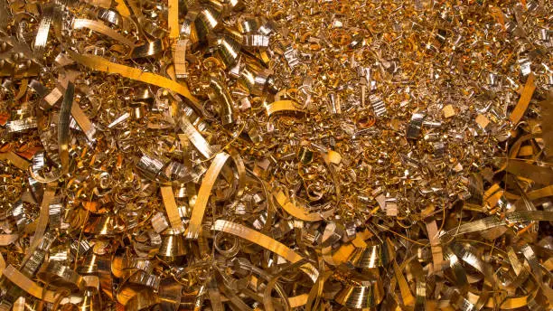 Photo of Golden background. Abstract gold background of metal shavings. Wallpaper or screensaver of yellow metallic chips. Processing of ferrous and non-ferrous metals in a factory or plant. Colored shavings.