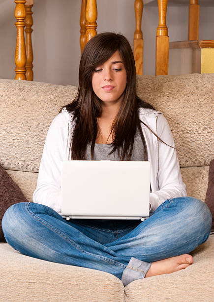 Young woman with laptop portable computer sitting on sofa stock photo