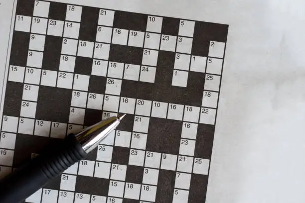 Photo of Crossword puzzle from newspaper with a pen to fill in answers