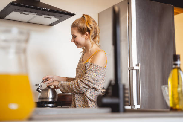 istock Positive delighted young woman looking at teapot 1201891715