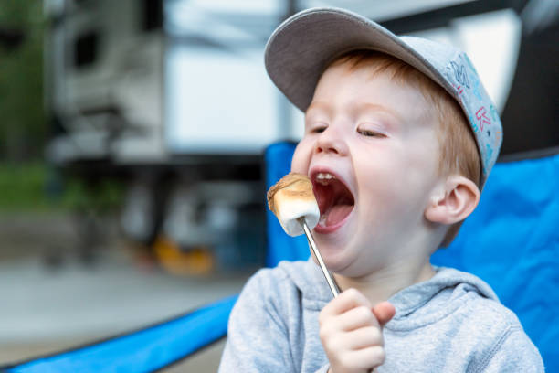 Little Redhead Boy Eating a Marshmallow in Camping in Summer