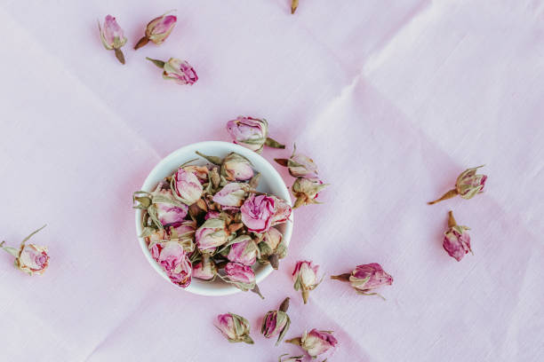 istock Dried roses in a white cup at pink pastel background. 1201896505