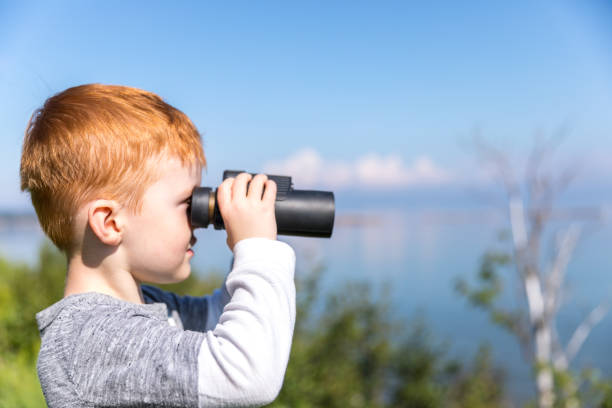 istock Little Redhead Boy Whale Watching With Binoculars in Camping in Summer 1201897625