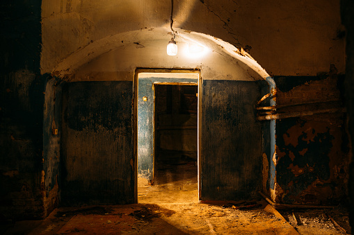 Old dark creepy abandoned basement with lamp.